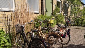 Bicycles parked in front of a building with a brick facade, a green door, and a window with blinds. - Explorers Club (Lund)