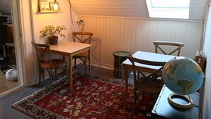 A cozy room with a wooden table, two chairs, a globe, and a red patterned rug. - Explorers Club (Lund)