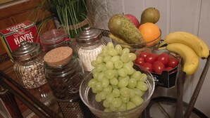 A kitchen counter with various food items including grapes, tomatoes, bananas, and a bowl of pears. - Explorers Club (Lund)