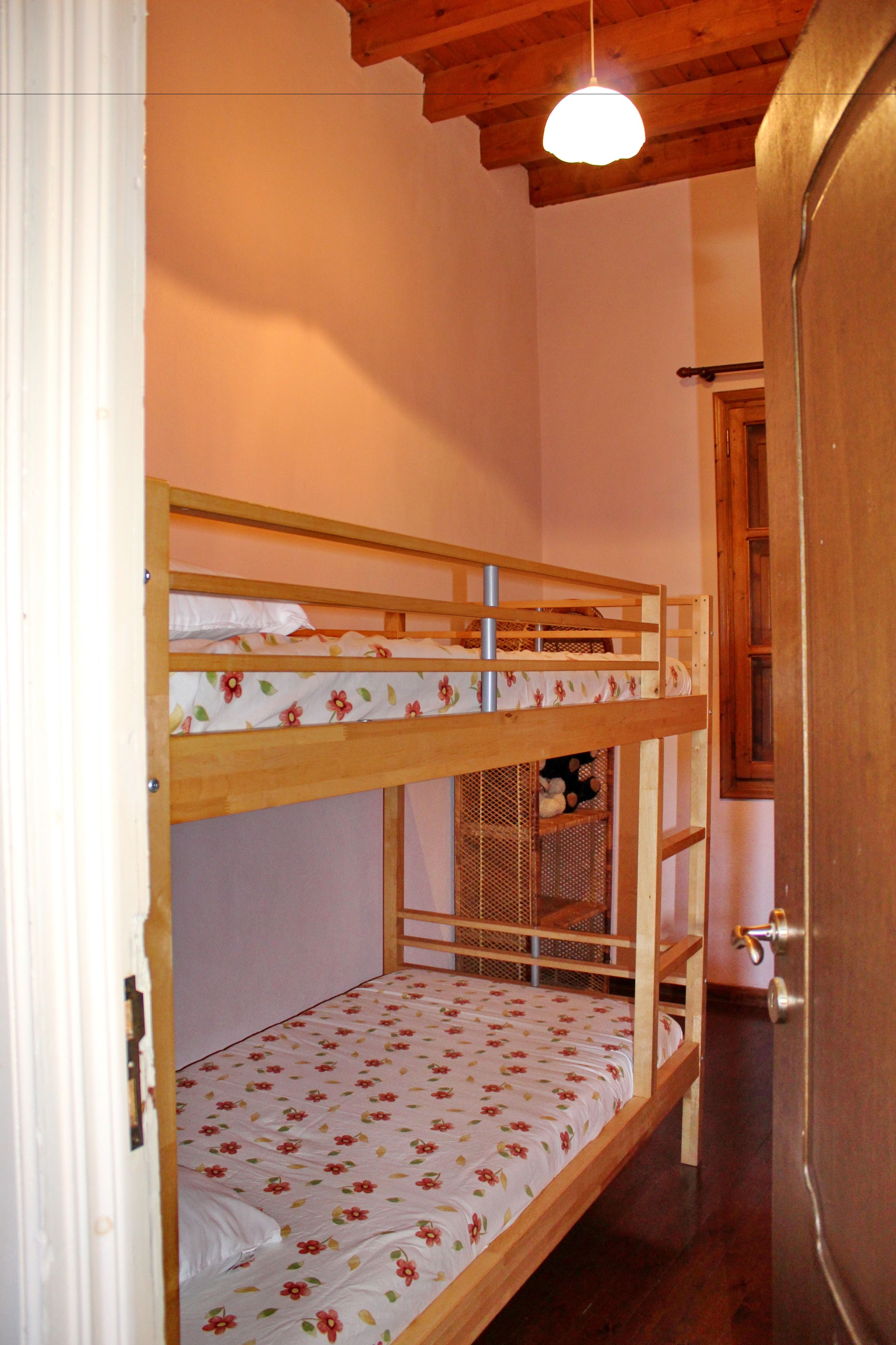 Habitación con literas, techo de madera y una lámpara.
