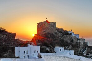 A coastal town with a prominent castle-like structure during sunset.