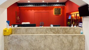 Ein Empfangsschalter mit roter Wand, einer traditionellen chinesischen Tür und einem Wandfernseher.