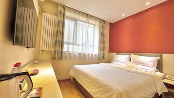 A hotel room with a bed, bedside table, and a mirror.
