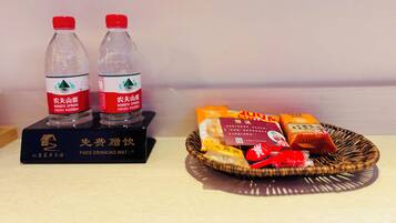 Two bottles of Nongfu Spring water and a basket of snacks on a table.