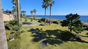 A coastal resort with palm trees, a paved walkway, and a view of the ocean. - Old Man and Sea Pension (Seogwipo)