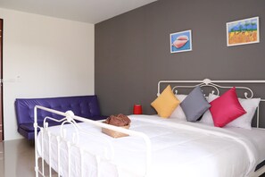 Ein Schlafzimmer mit weißem Metallbett, einem violetten Sofa und zwei Bildern an der Wand.