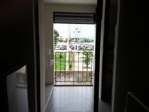 A view from a balcony with a metal railing, looking out onto a parking lot with several cars and a building in the background. - Apartment Khunpa (Koh Samui)