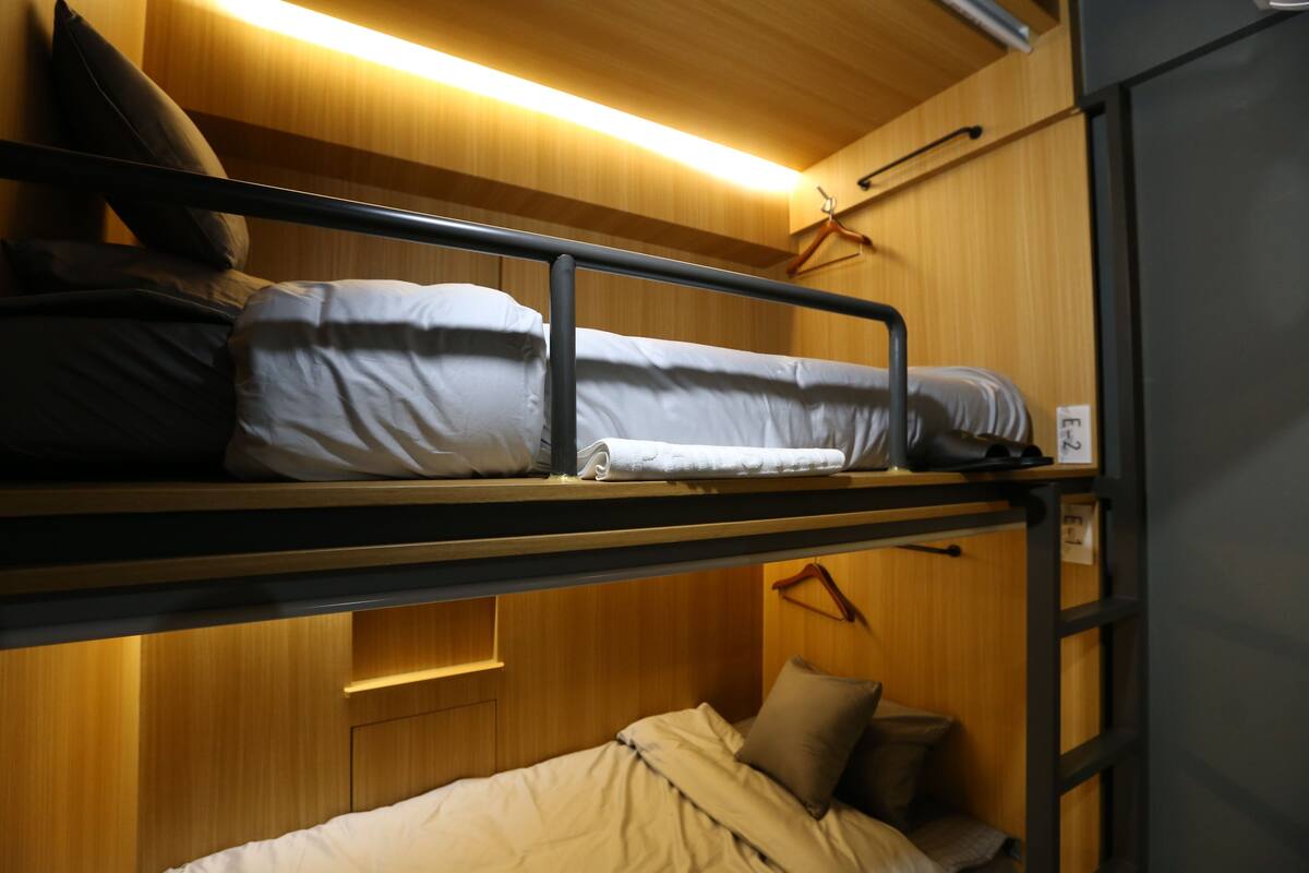 Una cama litera con cabecera de madera y una pequeña repisa encima.