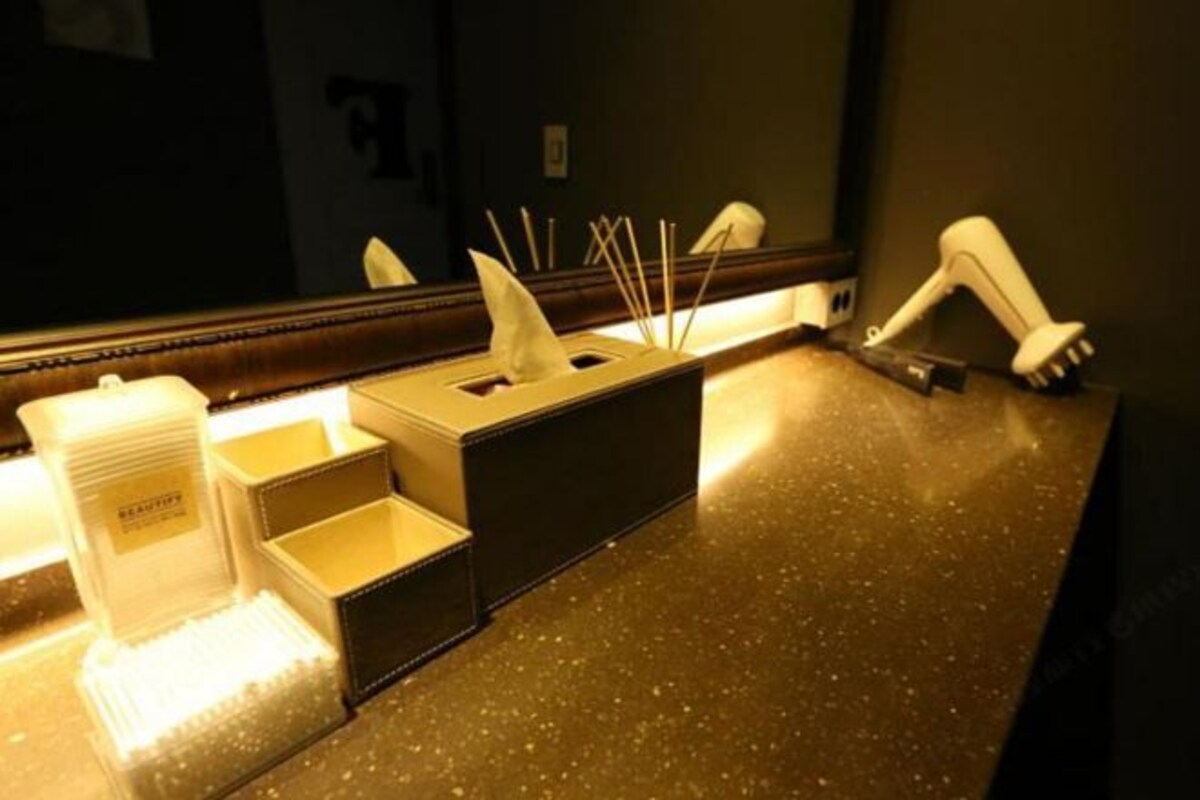 Une salle de bain d’hôtel équipée d’un miroir, d’un porte-serviettes et d’un distributeur de savon.