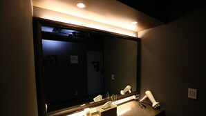 A bathroom with a large mirror, a sink, and a tissue box.