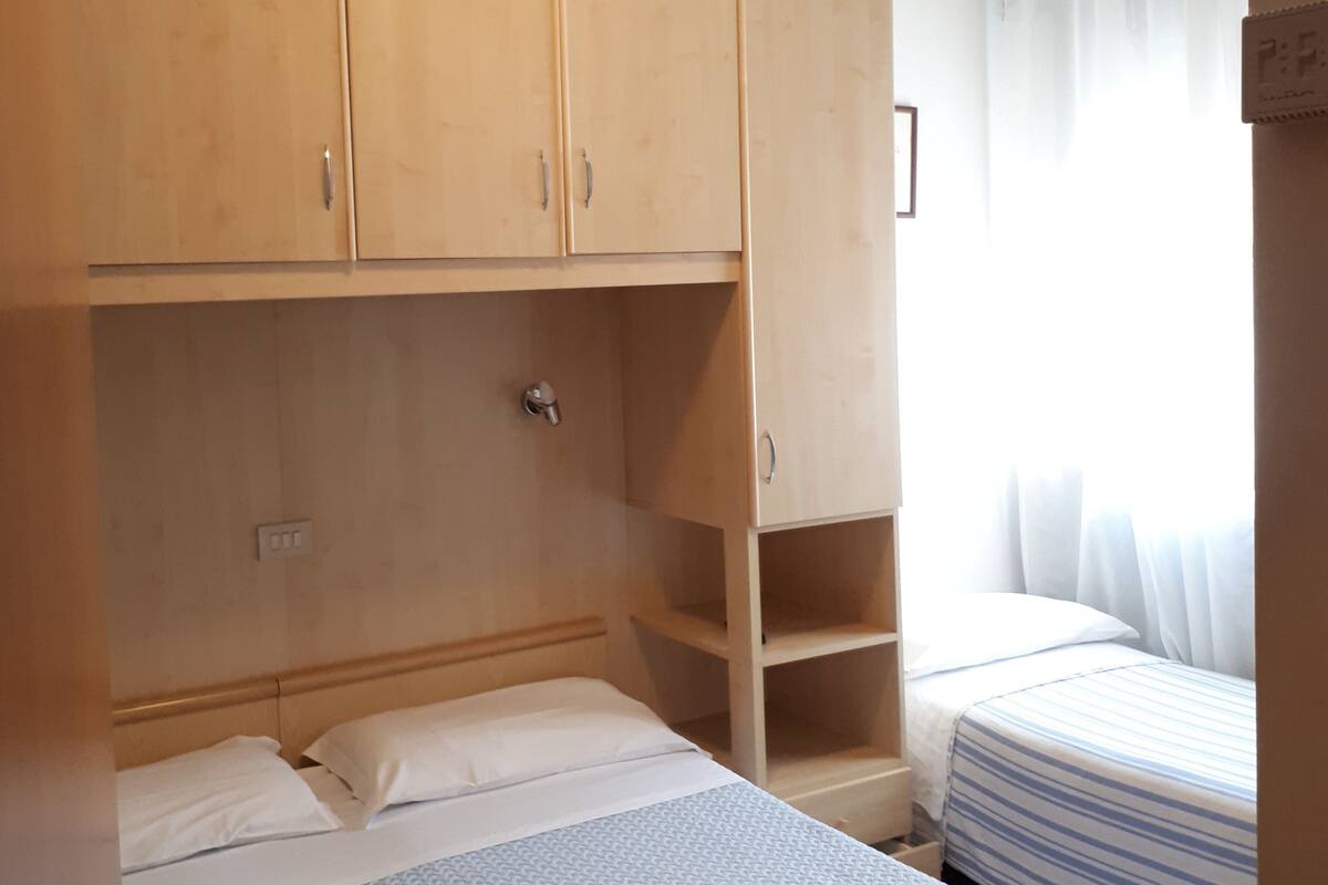 Un dormitorio con una cama individual, un armario de madera y una pequeña estantería.