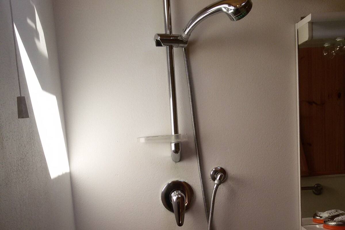 Un baño con ducha, lavamanos y espejo.
