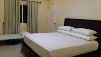 A room with a bed, a bench, and a door.