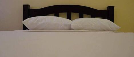 Cama com cabeceira escura e duas almofadas brancas.