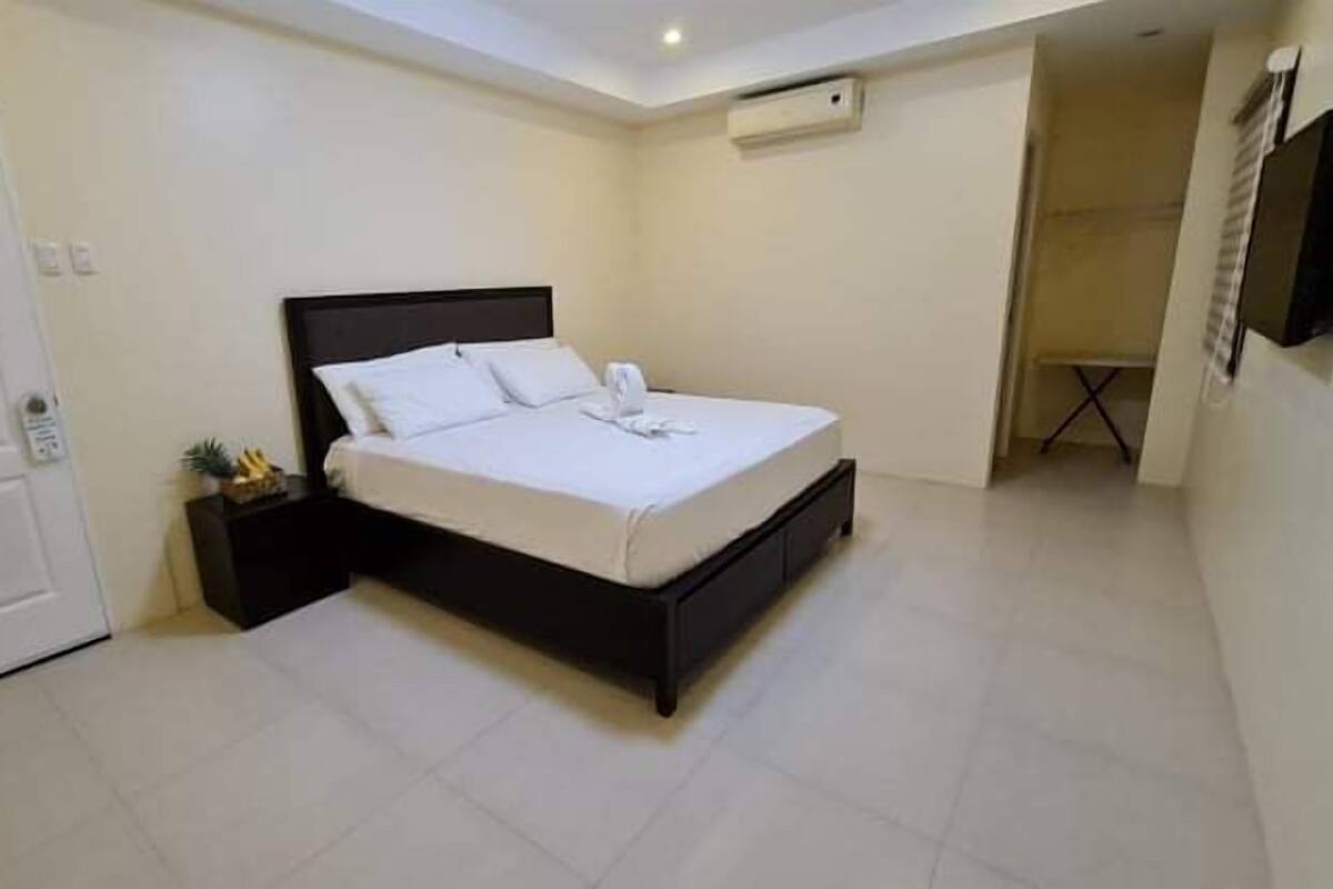 A bedroom with a bed, a nightstand, a door, and a wall-mounted air conditioner.