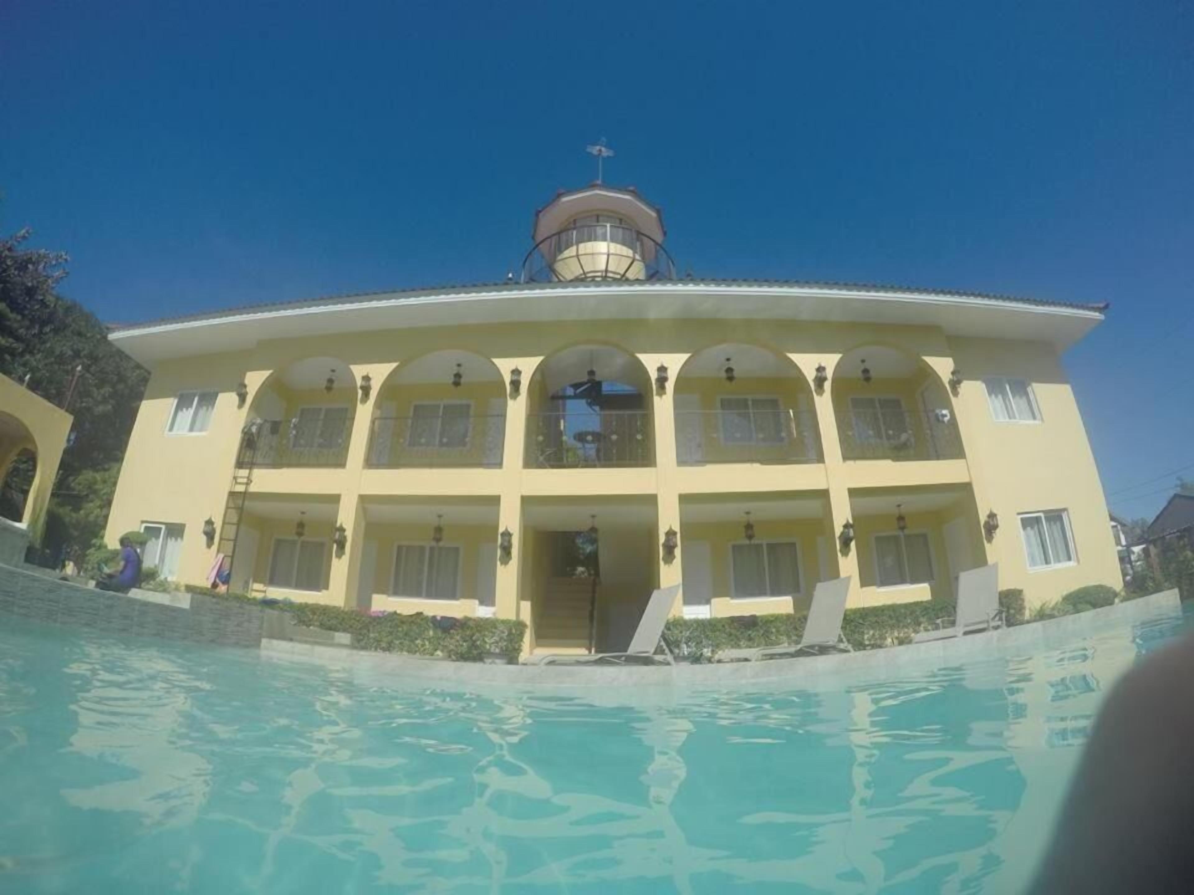 A large, yellow building with multiple balconies and a swimming pool in the foreground.