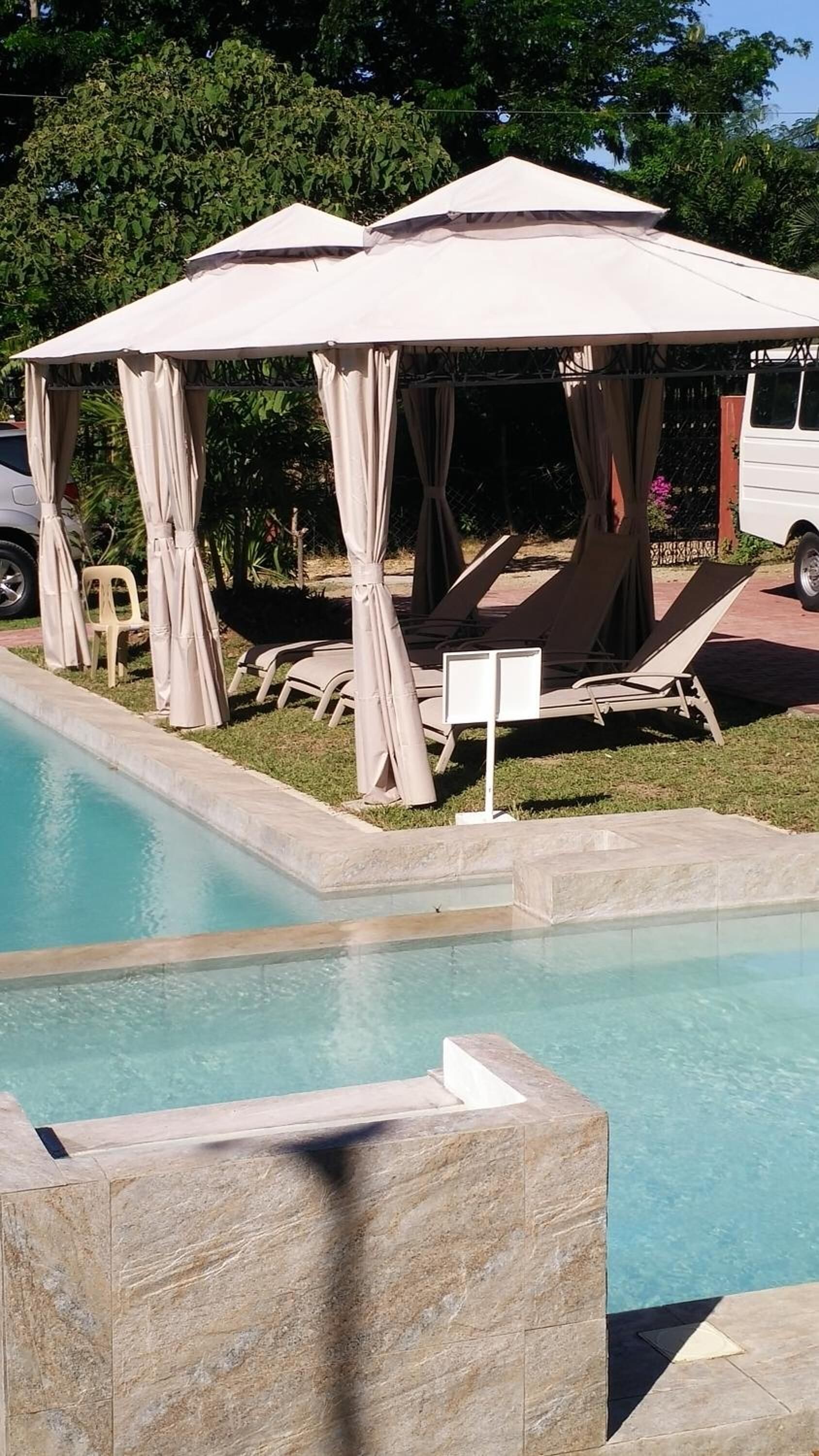 Zona de piscina con sillones de descanso y una zona de estar cubierta.