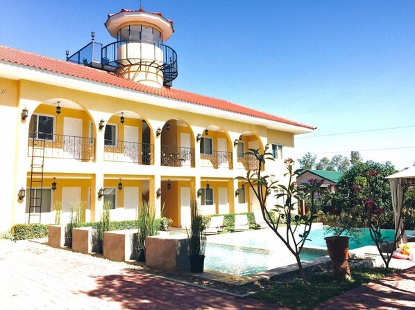 A multi-story building with balconies, a swimming pool, and outdoor seating areas. - Villa Del Faro (Calatagan)
