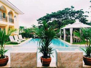A pool area with lounge chairs, a gazebo, and potted plants.