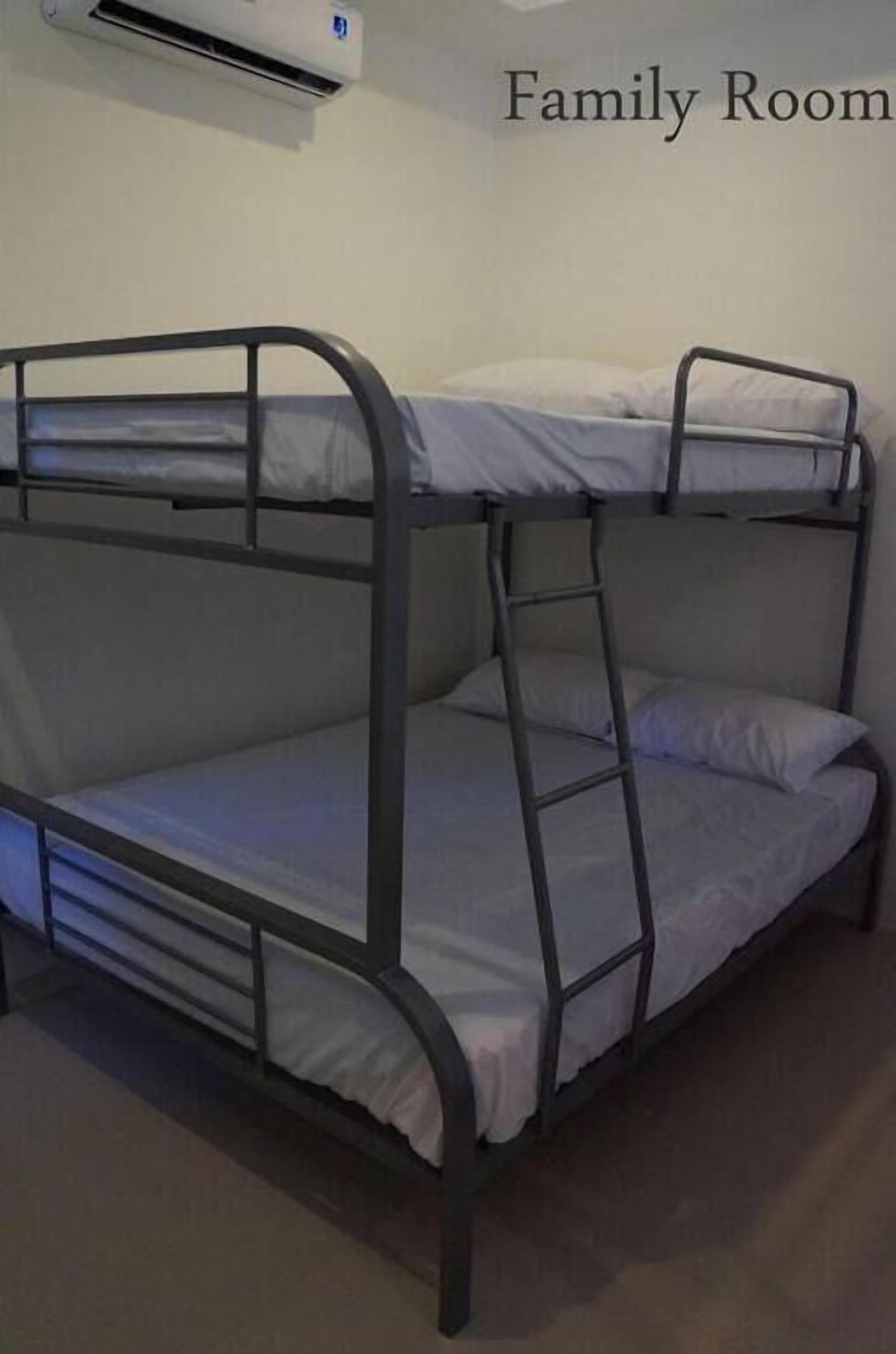 A bunk bed in a family room with an air conditioning unit above it.