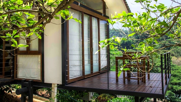 A wooden deck with a table and chairs, overlooking a lush green landscape. - Hotel Yo (Kandy)