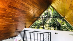 A wooden interior with a triangular skylight, a white wall, and a black railing. - Hotel Yo (Kandy)