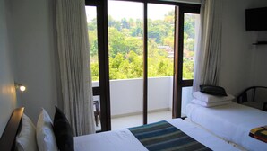 A hotel room with two beds, a large window with curtains, and a view of greenery outside. - Hotel Yo (Kandy)