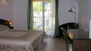 Un dormitorio con cama, escritorio, silla, lámpara y televisión.