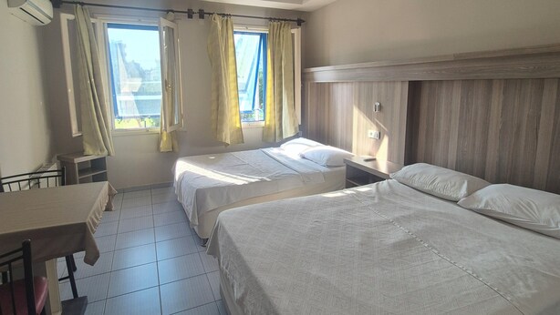 A hotel room with two beds, a desk, and a window with curtains. - Cihanay Hotel (Antalya)