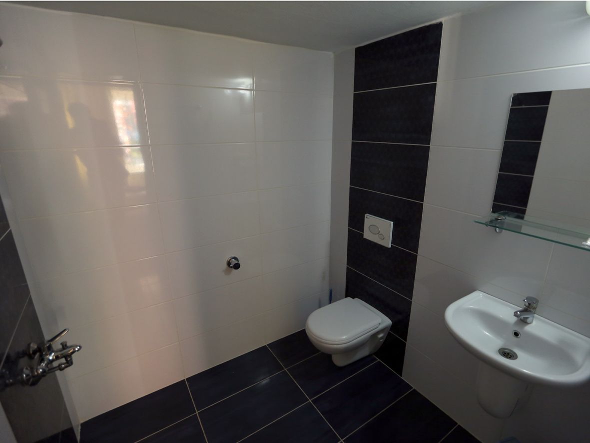 A bathroom with a toilet, sink, and shower area.