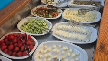 Un bufé con diversos alimentos, incluyendo frutas, verduras y queso.
