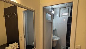Un baño estrecho con espejo, lavamanos e inodoro.
