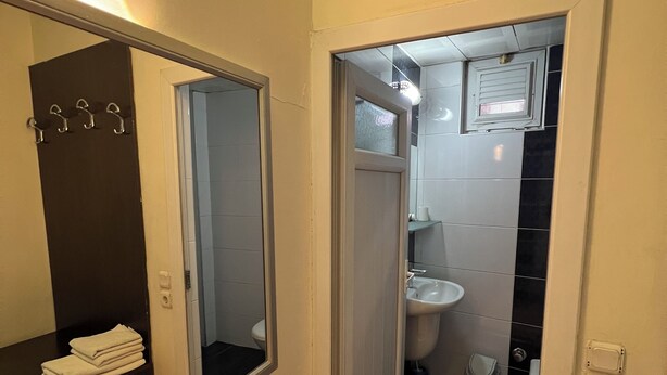 A narrow bathroom with a mirror, a sink, and a toilet. - Cihanay Hotel (Antalya)