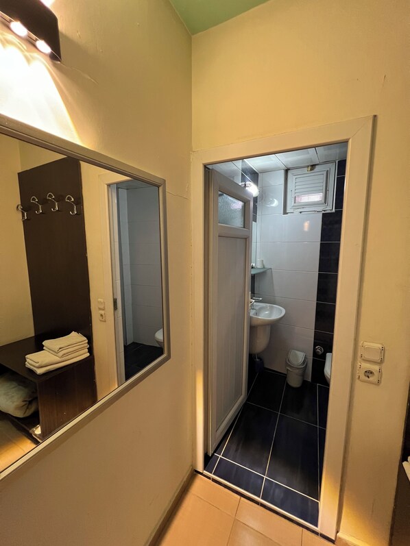 A narrow bathroom with a mirror, a sink, and a toilet.