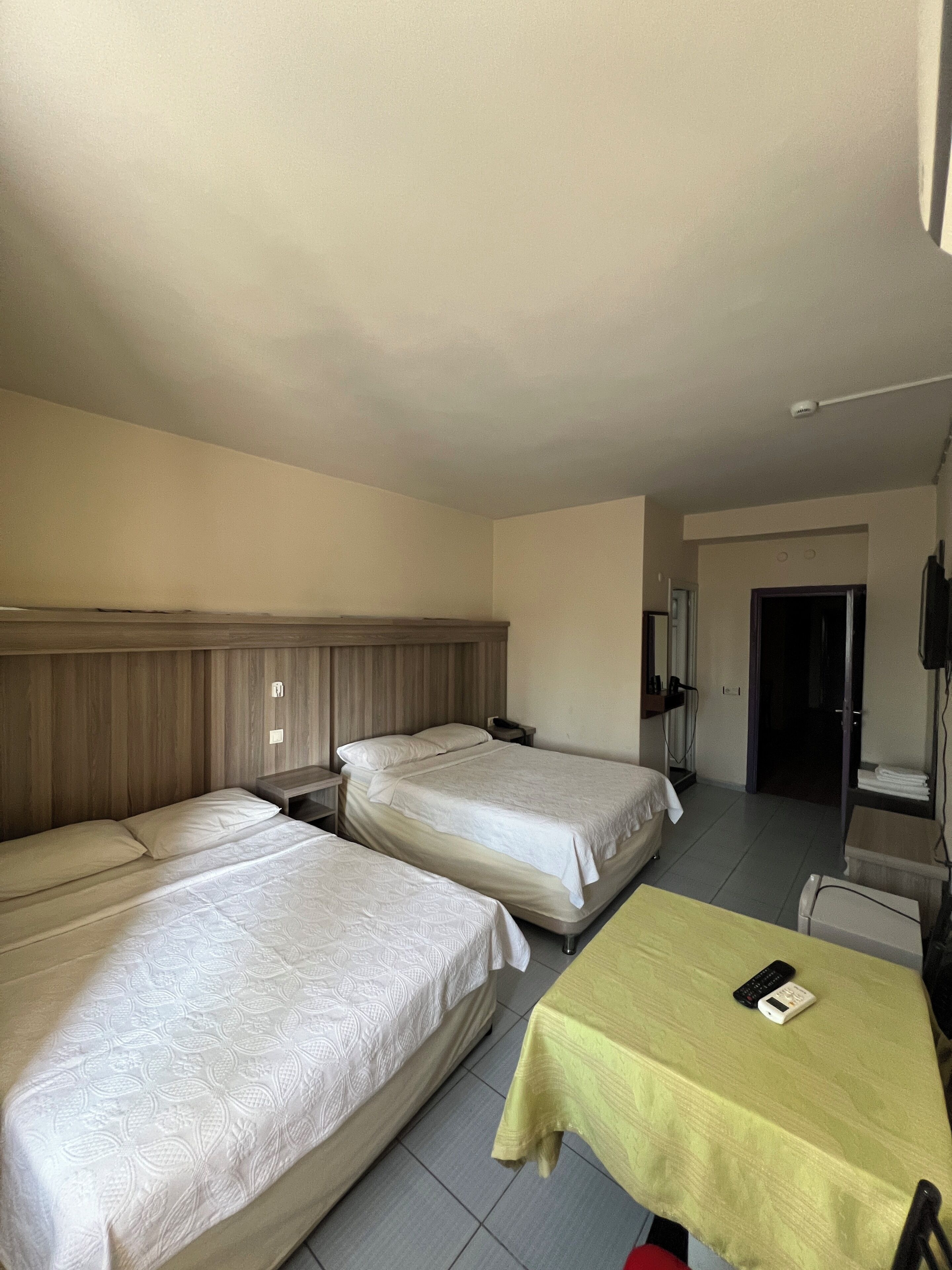 Een hotelkamer met twee bedden, een kleine tafel, een televisie en een badkamers deur.