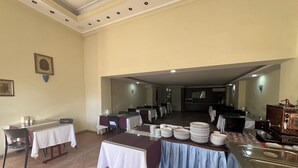 A dining area with tables set for service, a buffet station, and a kitchen in the background. - Cihanay Hotel (Antalya)