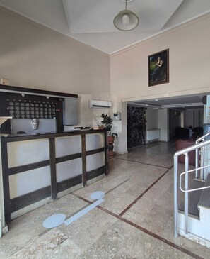 A reception area with a counter, a painting on the wall, and a marble floor.