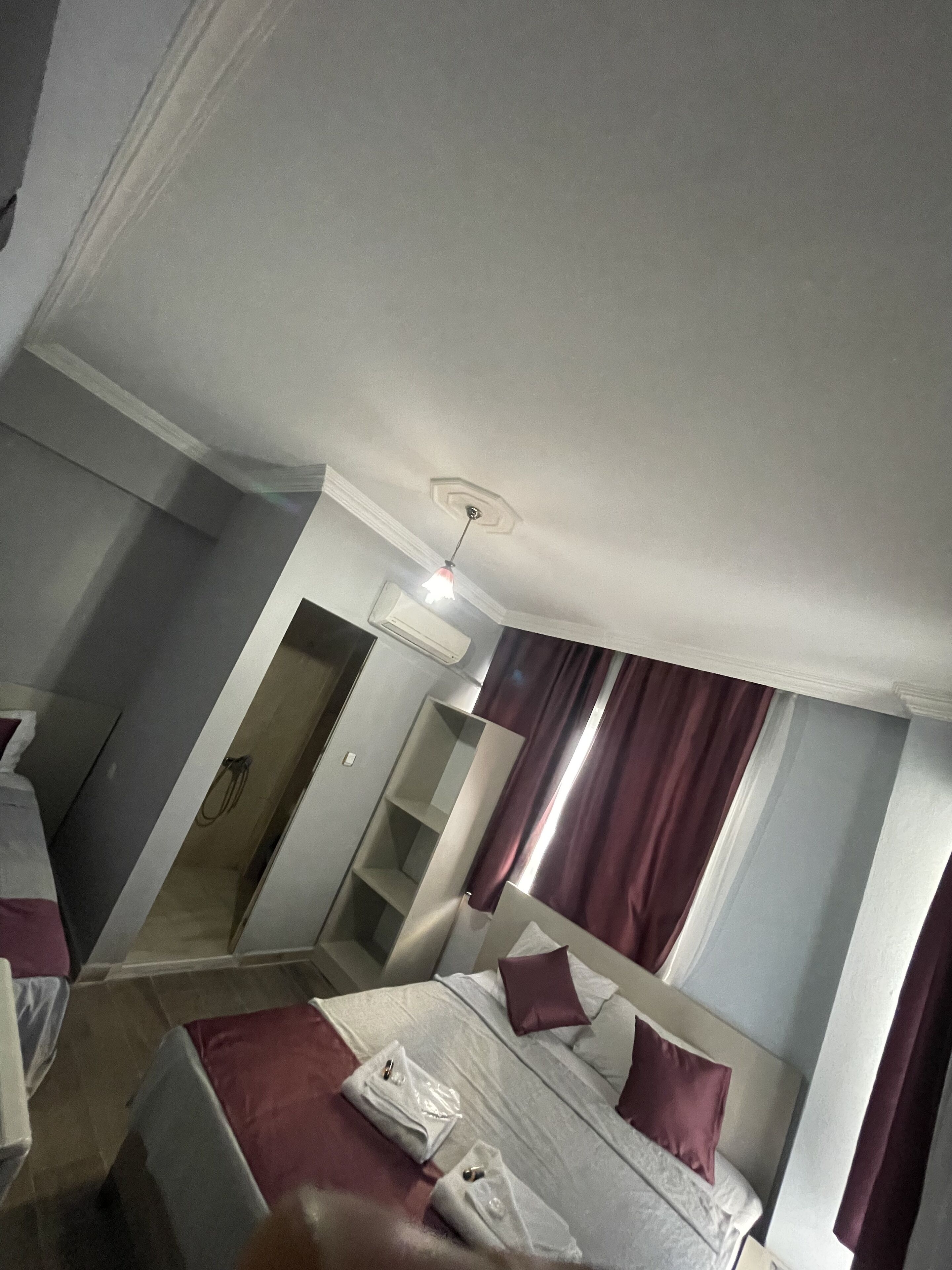 A hotel room with a bed, a bedside table, a wardrobe, and a ceiling light.