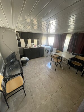 Una cucina funzionale con lavatrice, un tavolo da pranzo con sedie e un piccolo angolo relax.