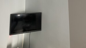 A room with a flat-screen TV mounted on the wall, a white ceiling, and a plain wall. - Ersoy Aga Otel (Antalya)