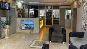 A hotel lobby with a reception desk, seating area, and a large screen displaying a scenic view. - Ersoy Aga Otel (Antalya)
