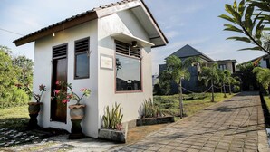 Um pequeno edifício térreo com telhado de azulejos, placa de escritório de segurança e plantas em vasos.