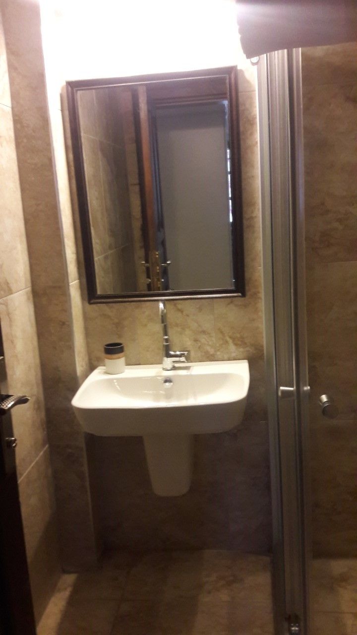 A bathroom with a white sink, a mirror, and a glass shower enclosure.