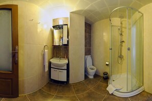 A bathroom with a glass-enclosed shower, a sink, a toilet, and a mirror.