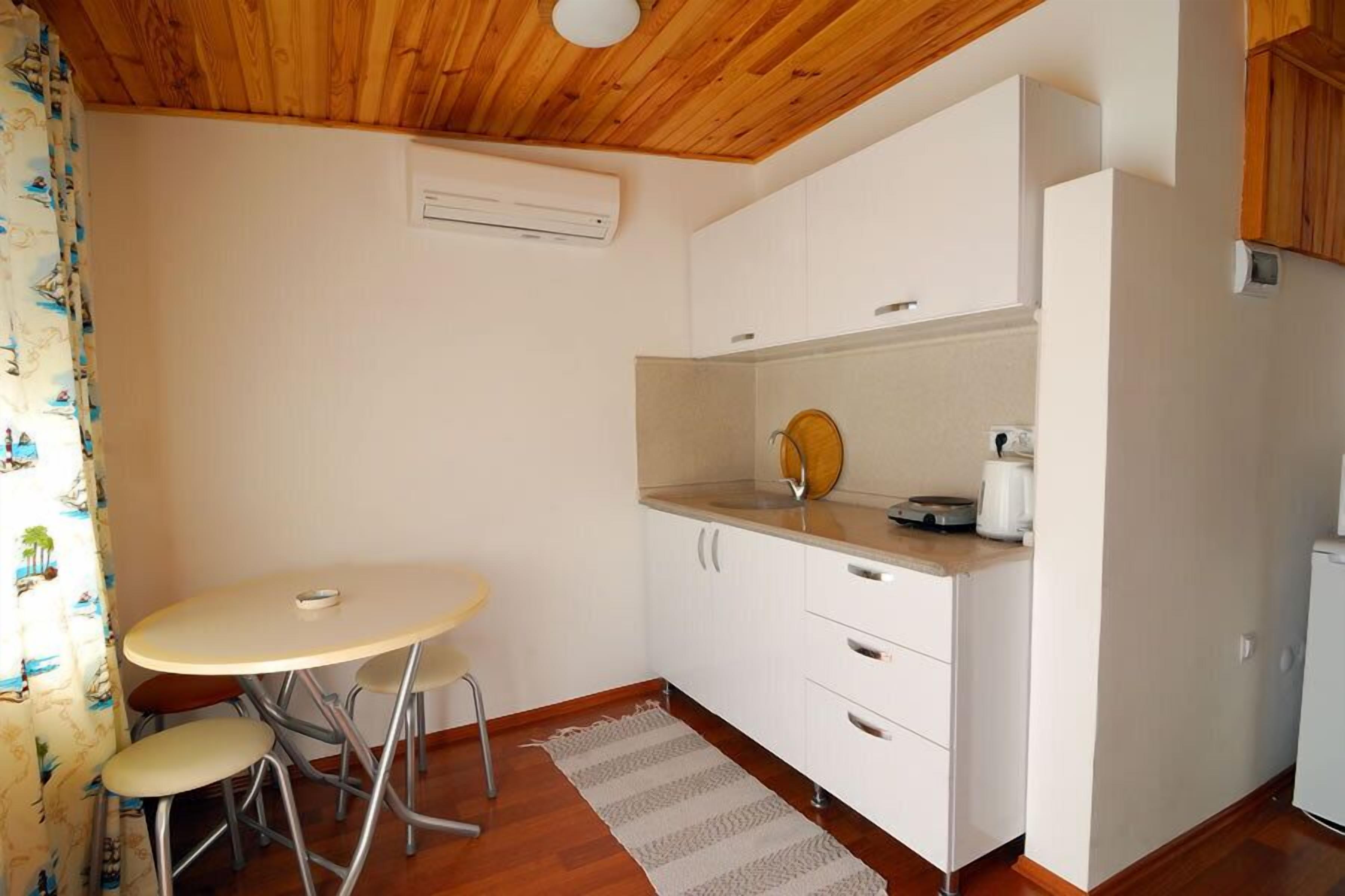 Una cocina pequeña con una mesa redonda, dos sillas, una cafetera y un refrigerador.