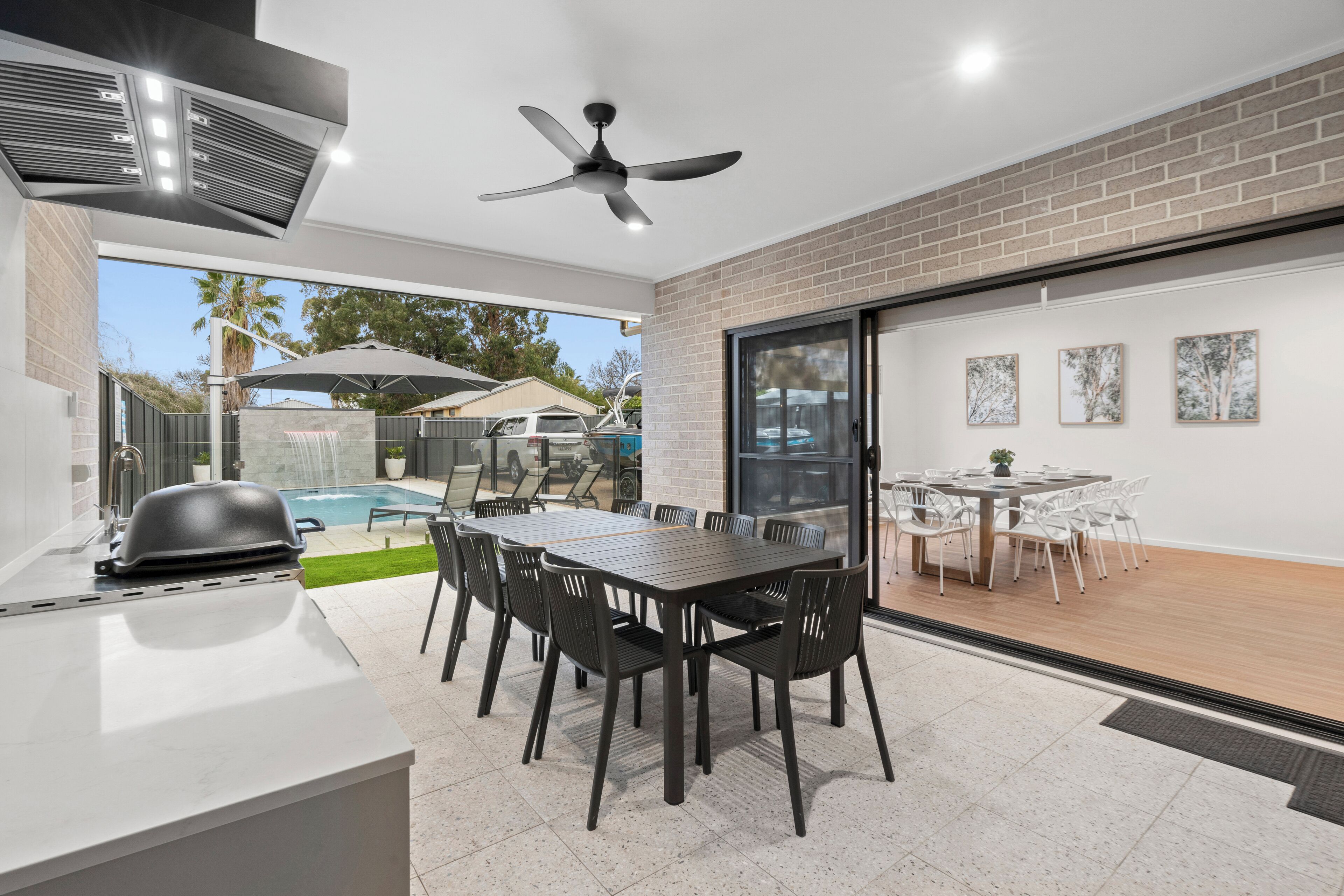 An outdoor patio with a barbecue grill, a pool, and a dining area with chairs and tables.