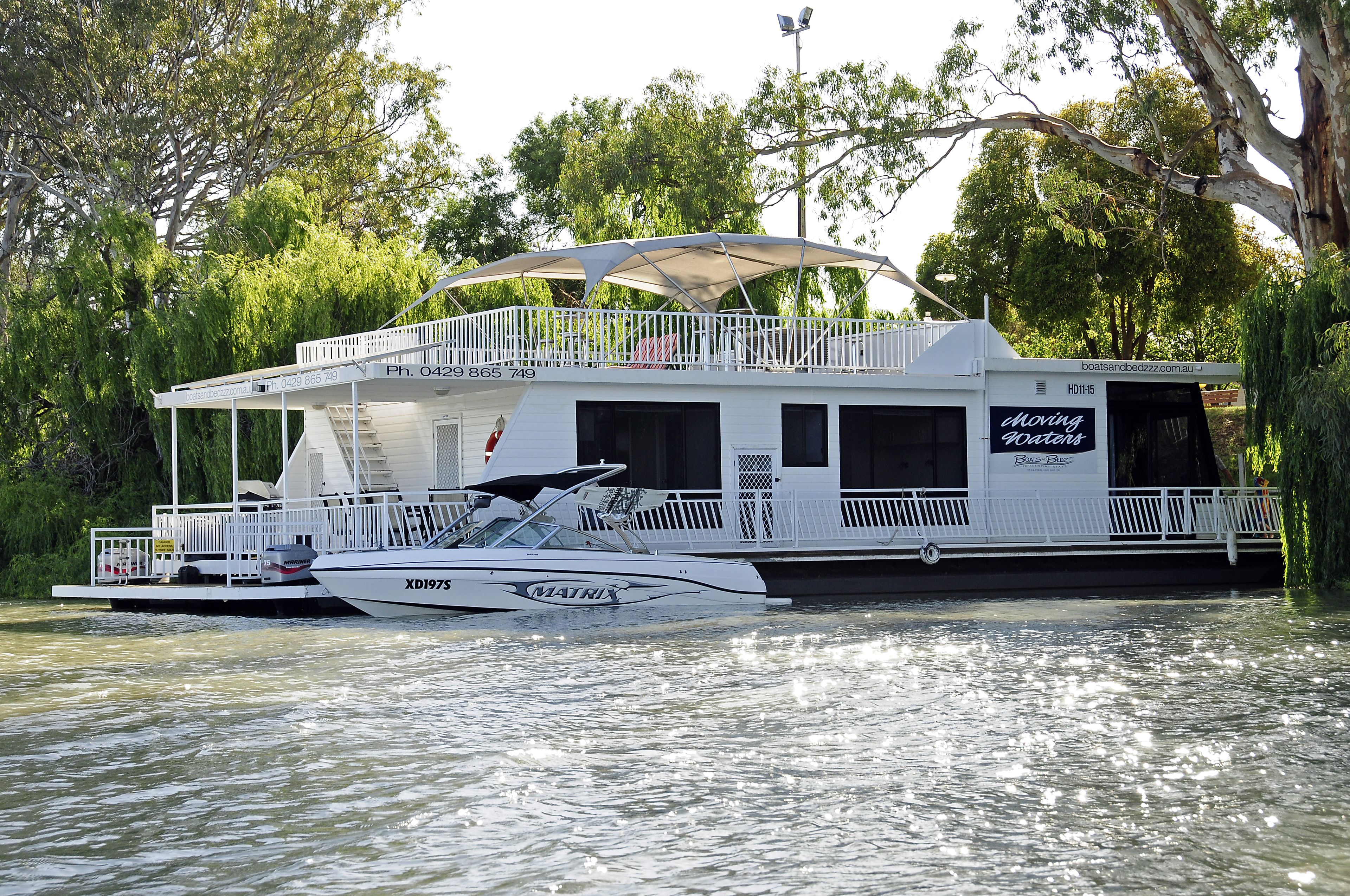 Une péniche dotée d’une terrasse couverte, d’un balcon et d’un panneau indiquant « Eaux mouvantes ».