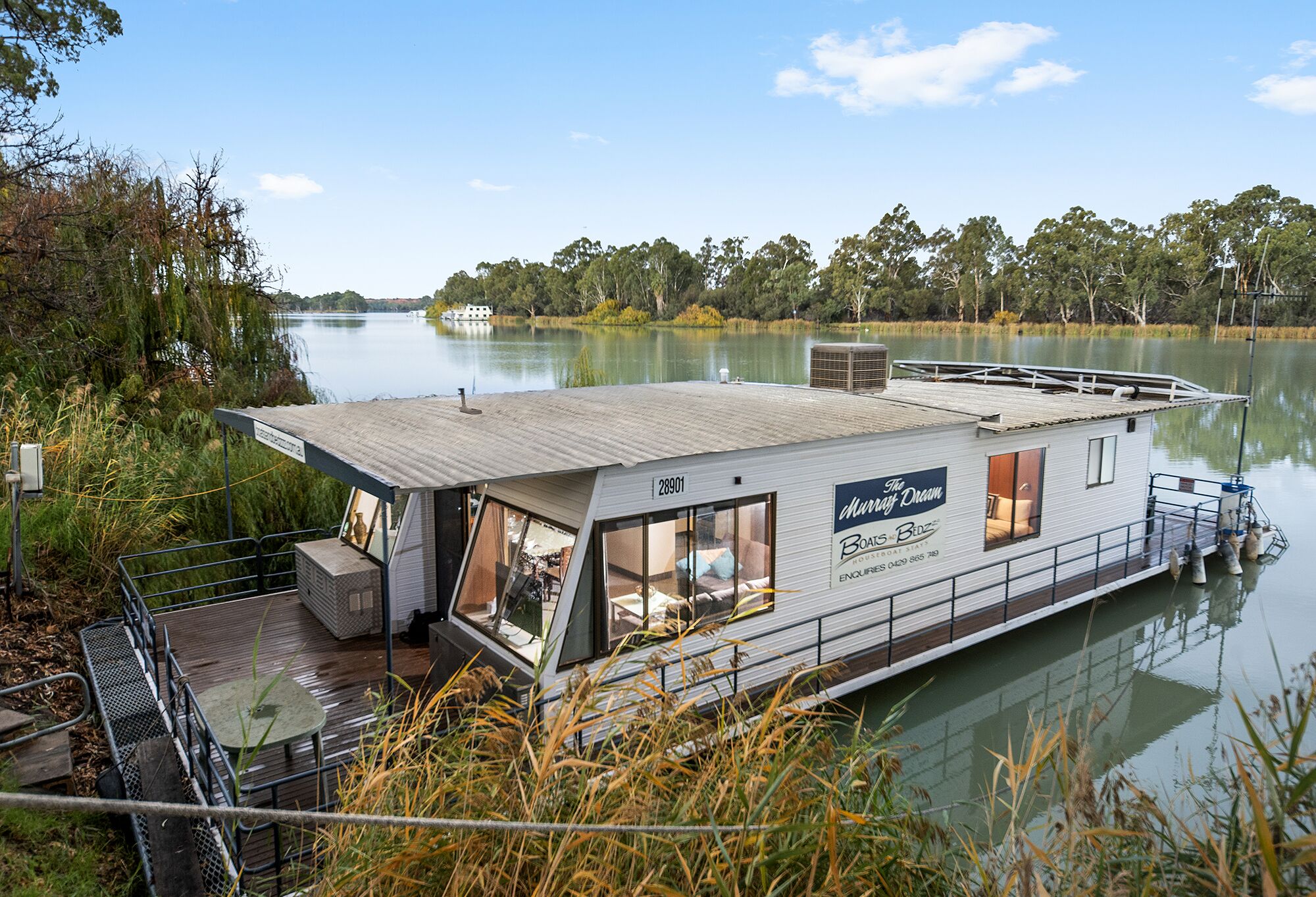 A houseboat with a deck, windows, and a sign that reads "The Dream."