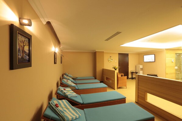 Une salle de spa équipée de plusieurs tables de massage, d’un comptoir d’accueil et d’un téléviseur fixé au mur.