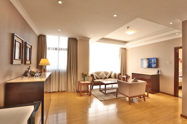 Une chambre d’hôtel moderne équipée d’un canapé, d’un fauteuil et d’un petit bureau avec une lampe.